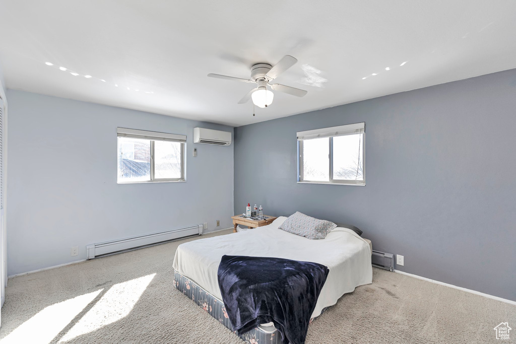 Bedroom with a baseboard radiator, light carpet, an AC wall unit, and ceiling fan