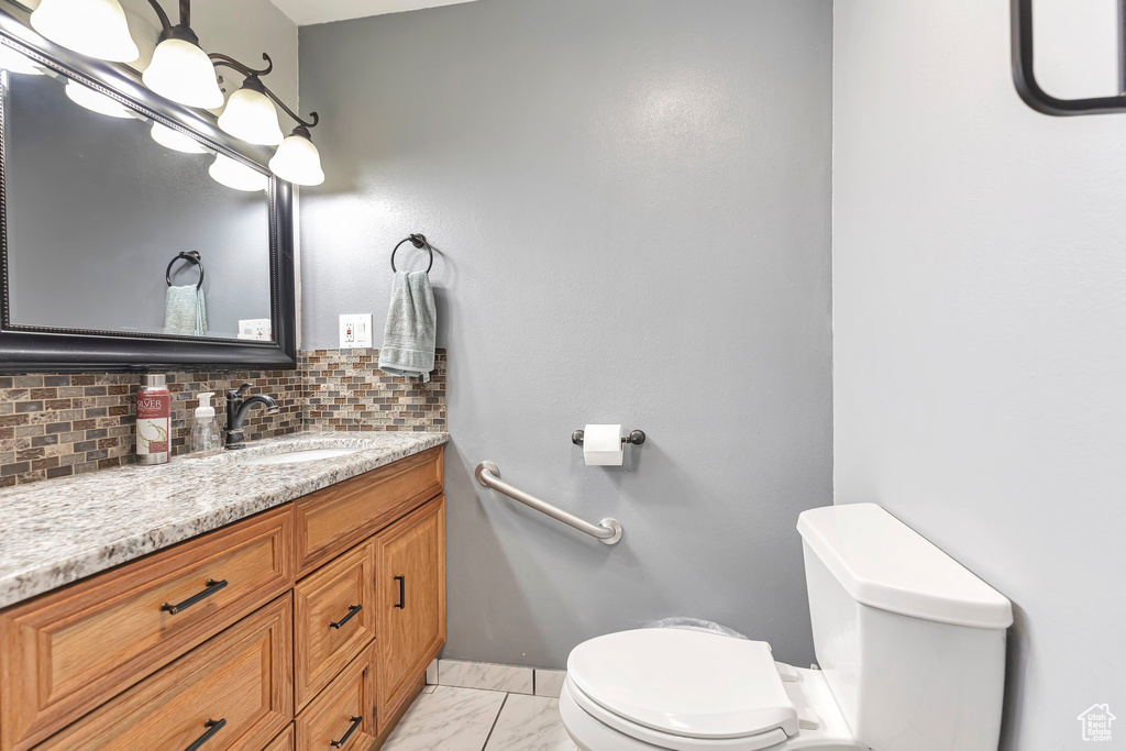 Bathroom with vanity, toilet, tasteful backsplash, and tile floors