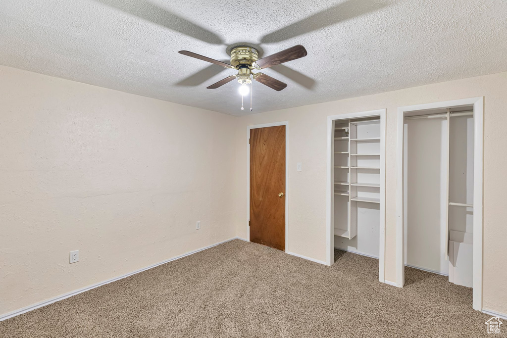 Unfurnished bedroom with light colored carpet, multiple closets, and ceiling fan