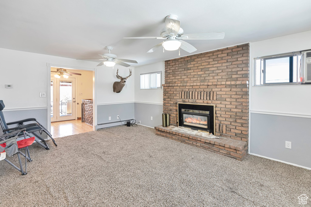 Interior space featuring a brick fireplace, light carpet, a baseboard radiator, and ceiling fan