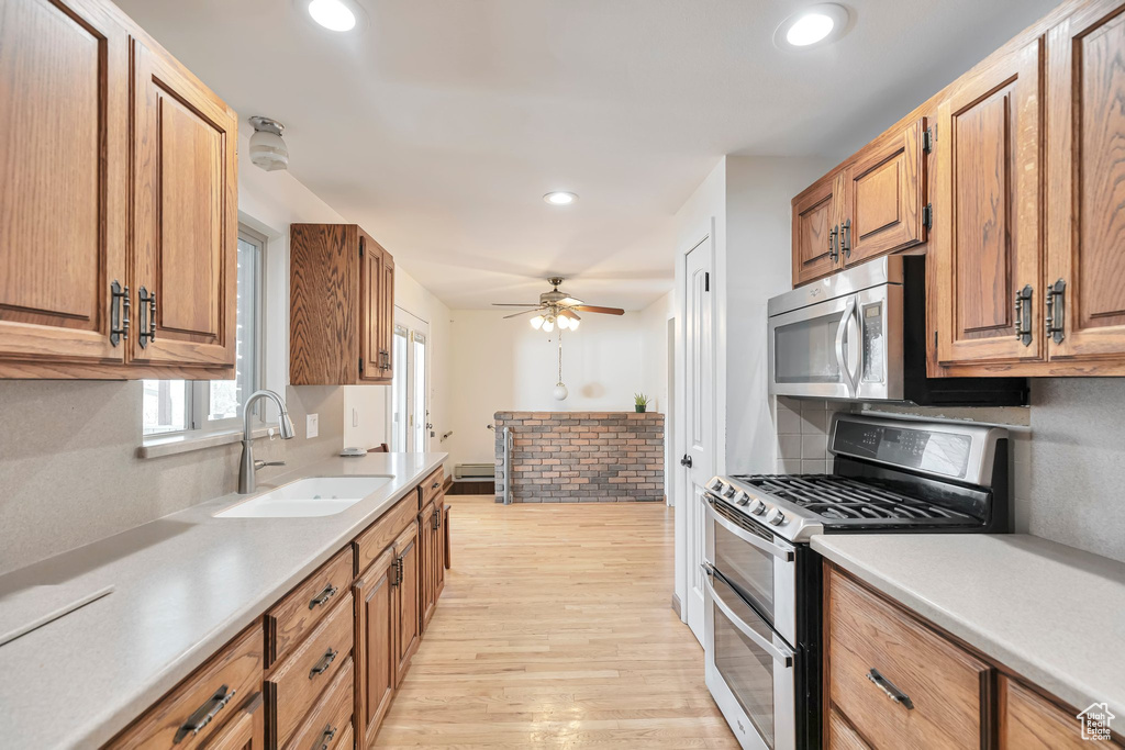 Kitchen featuring tasteful backsplash, appliances with stainless steel finishes, ceiling fan, sink, and light hardwood / wood-style flooring