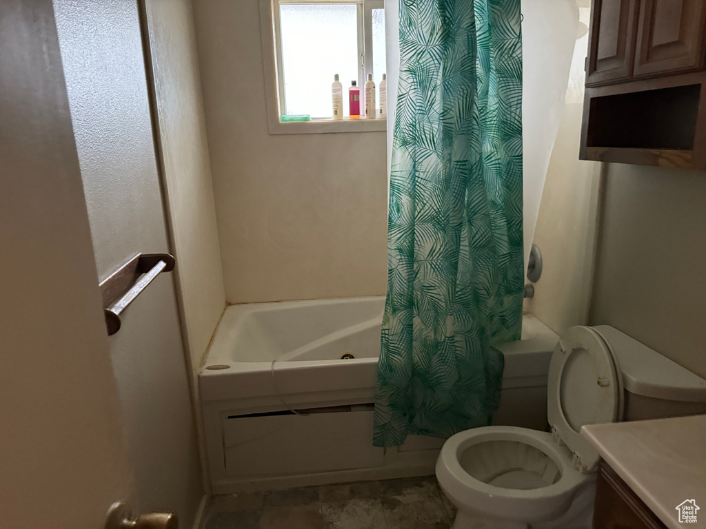 Bathroom with toilet, shower / tub combo, and tile flooring