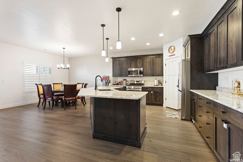Kitchen featuring decorative light fixtures, stainless steel appliances, hardwood / wood-style floors, and a chandelier