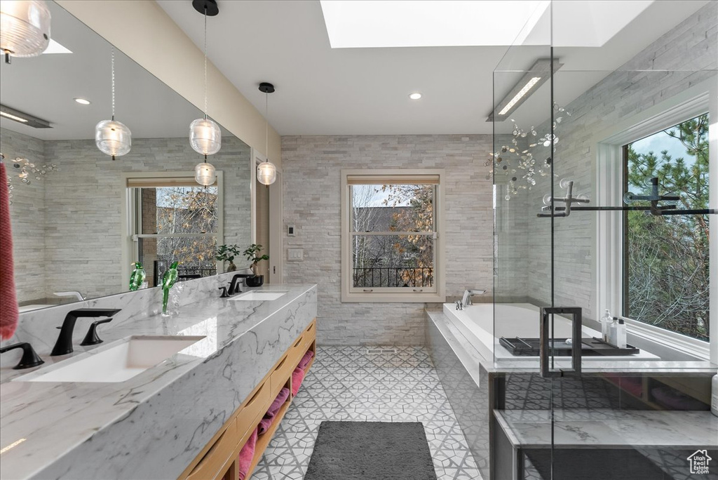 Bathroom featuring tile flooring, tile walls, large vanity, and a healthy amount of sunlight