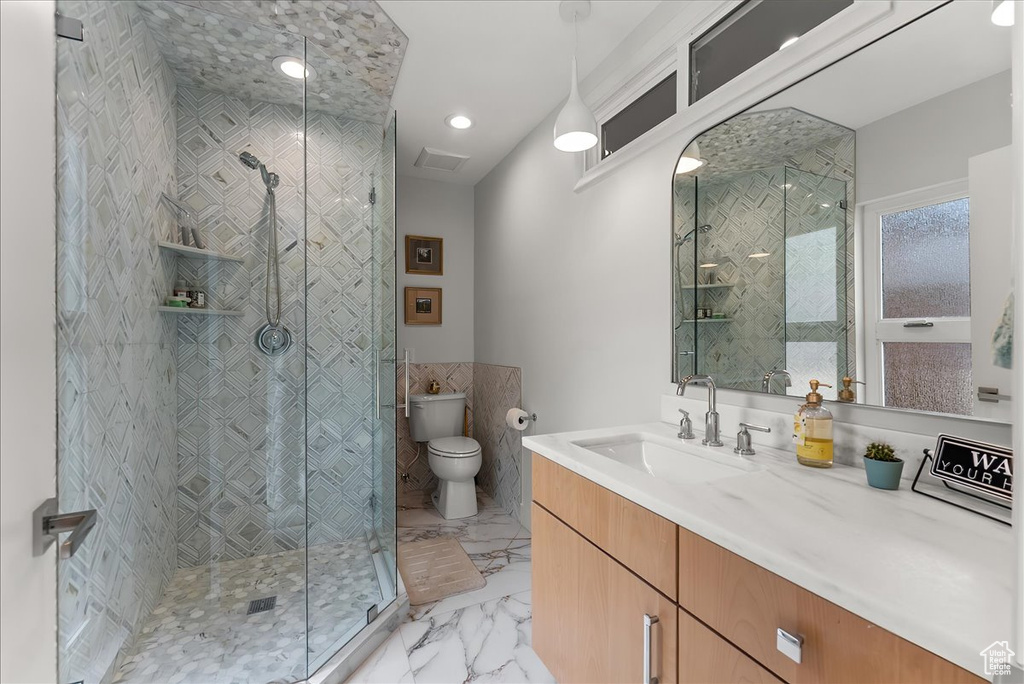Bathroom featuring an enclosed shower, toilet, vanity with extensive cabinet space, and tile floors