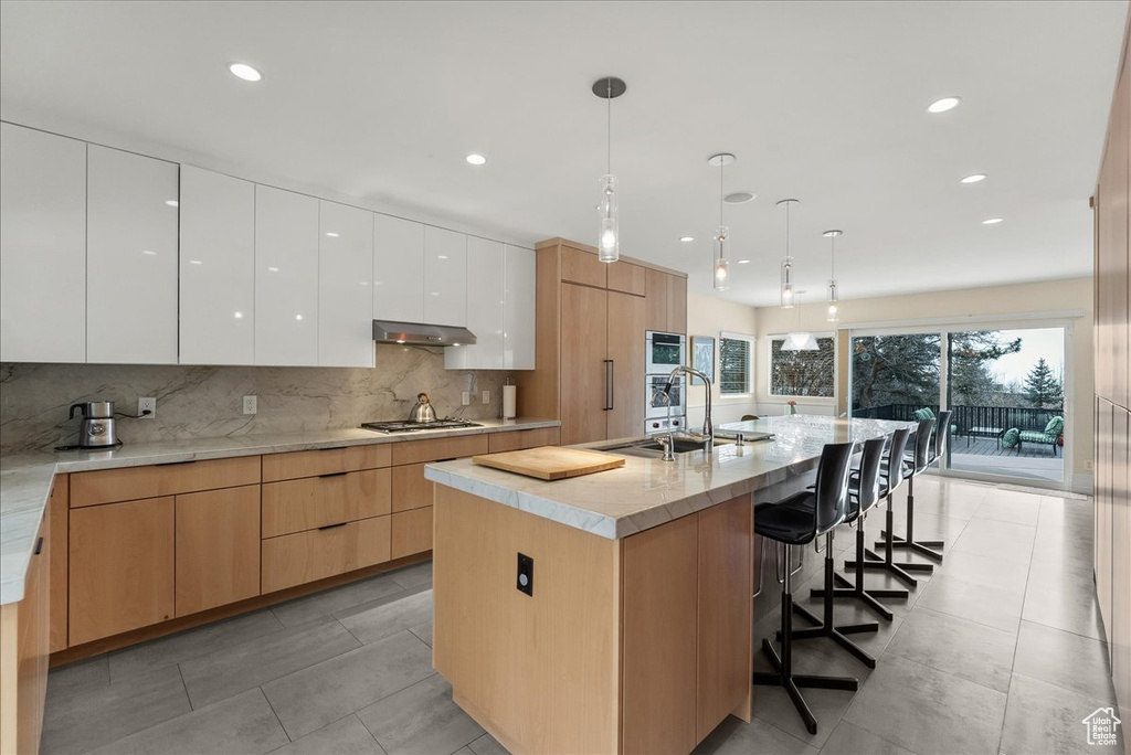 Kitchen featuring white cabinetry, sink, a breakfast bar, and a kitchen island with sink
