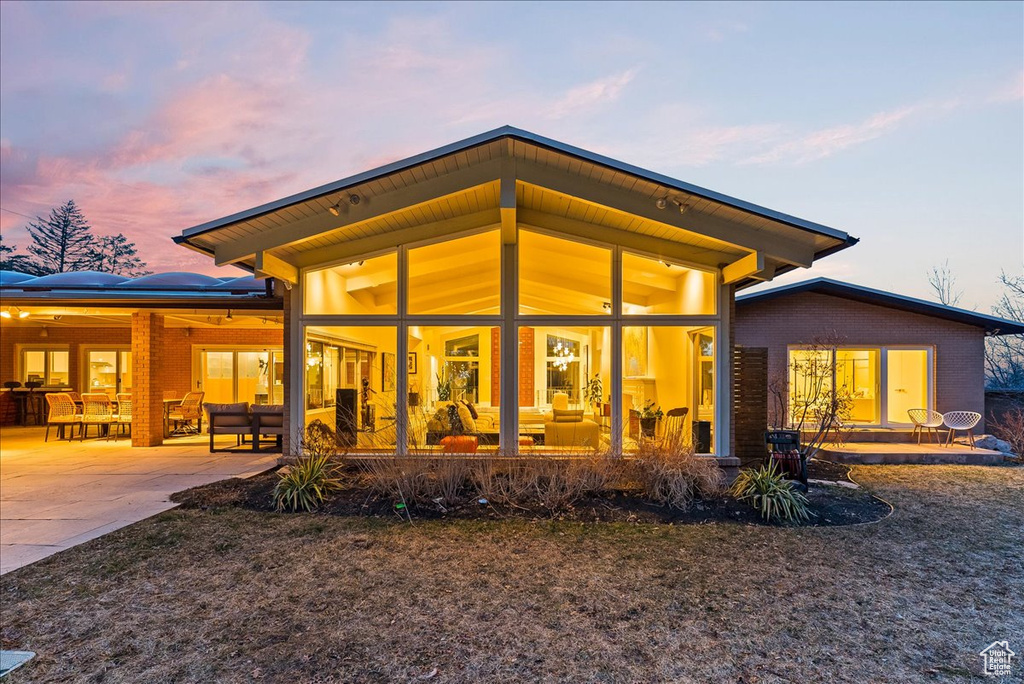 Back house at dusk with an outdoor hangout area, a patio, and ceiling fan