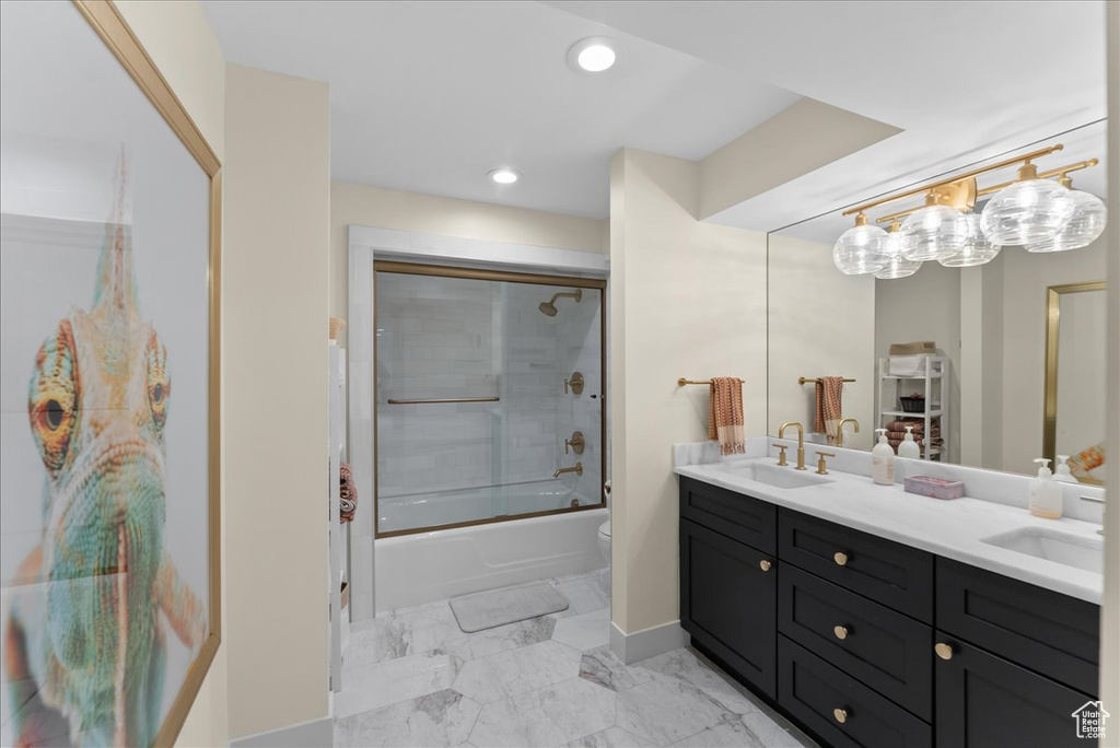 Full bathroom with a notable chandelier, dual bowl vanity, toilet, tile floors, and combined bath / shower with glass door