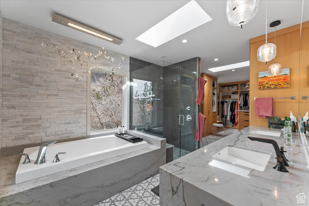 Bathroom with a skylight, tile flooring, separate shower and tub, and dual bowl vanity