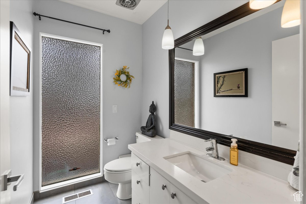Bathroom featuring vanity, toilet, tile floors, and a shower with shower door