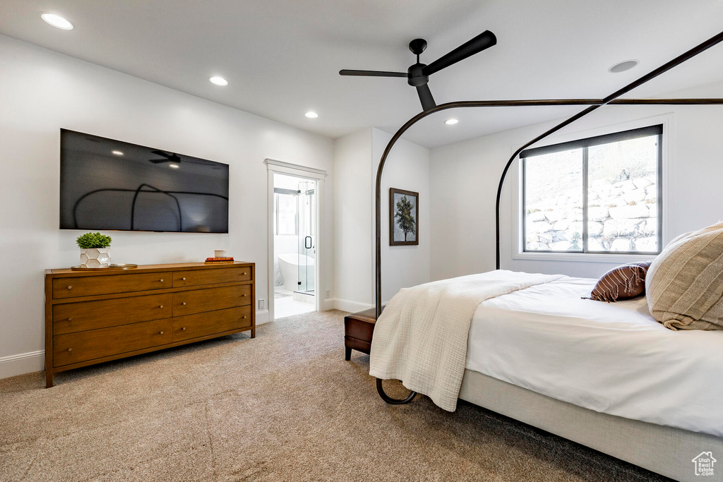 Bedroom featuring ceiling fan, light colored carpet, and ensuite bath