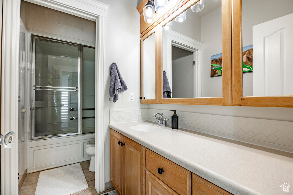 Full bathroom featuring shower / bath combination with glass door, tile patterned flooring, toilet, and vanity