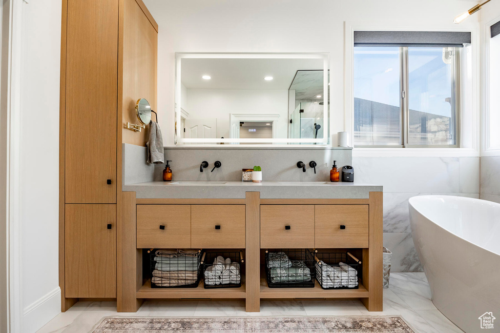 Bathroom with tile patterned floors, vanity, and a tub to relax in