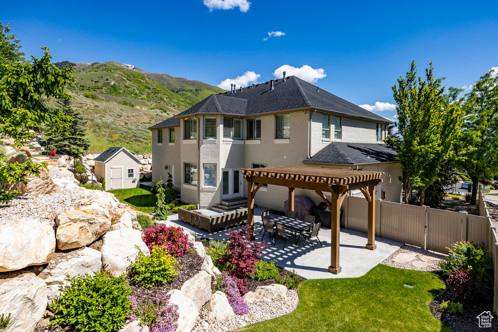 Back of property featuring a pergola, a mountain view, a patio, and a storage unit