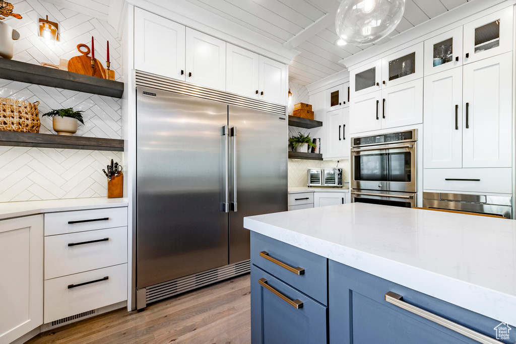 Kitchen featuring stainless steel appliances, light hardwood / wood-style flooring, white cabinets, and tasteful backsplash