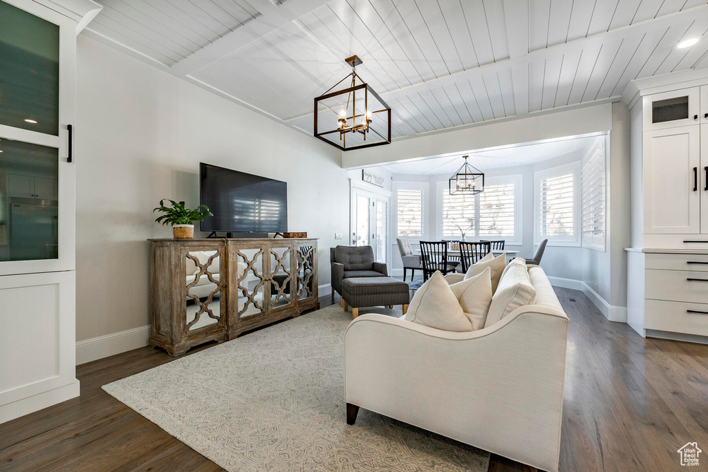 Living room featuring dark wood-type flooring, a chandelier, and wooden ceiling