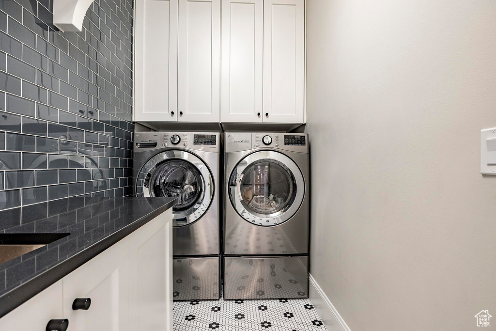 Washroom featuring washer and clothes dryer, tile patterned flooring, and cabinets