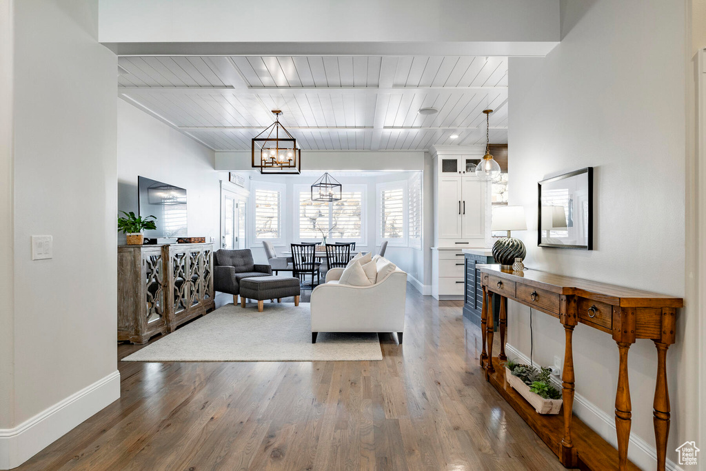 Living room with a notable chandelier, hardwood / wood-style floors, and wooden ceiling