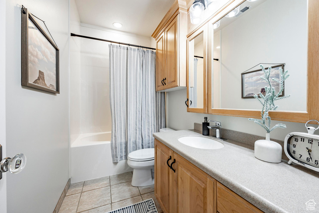 Full bathroom with tile patterned flooring, shower / bath combination with curtain, toilet, and vanity