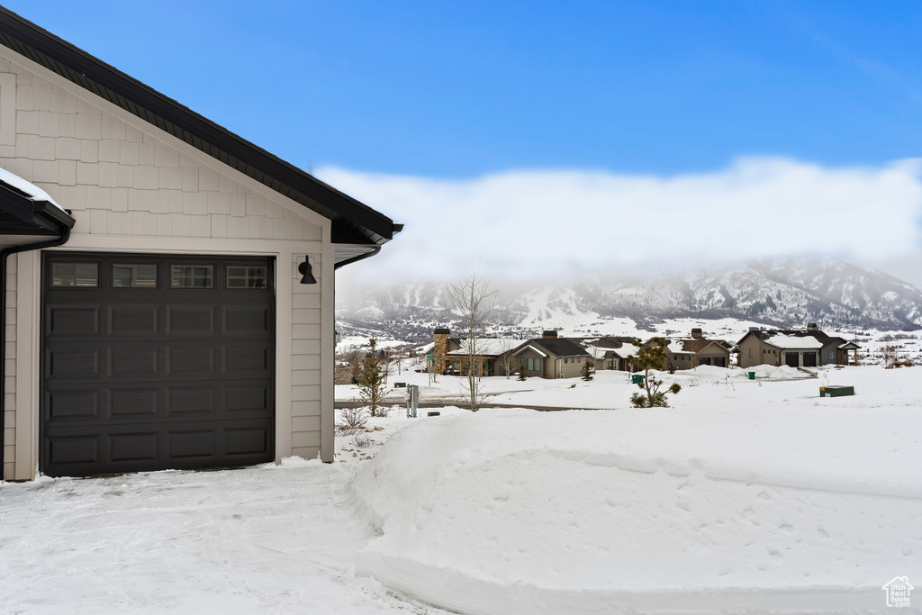 Yard covered in snow with a mountain view and a garage