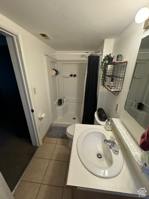 Bathroom featuring walk in shower, tile flooring, vanity, and toilet