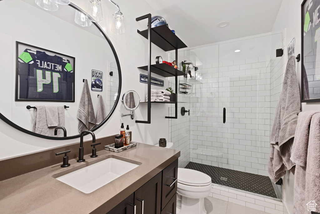 Bathroom featuring a shower with shower door, tile floors, toilet, and vanity