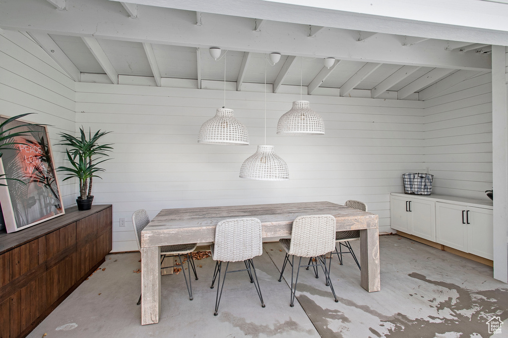 Dining area with vaulted ceiling with beams and wood walls