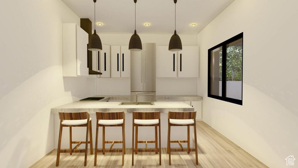 Kitchen with hanging light fixtures, a breakfast bar area, light hardwood / wood-style flooring, white cabinetry, and kitchen peninsula