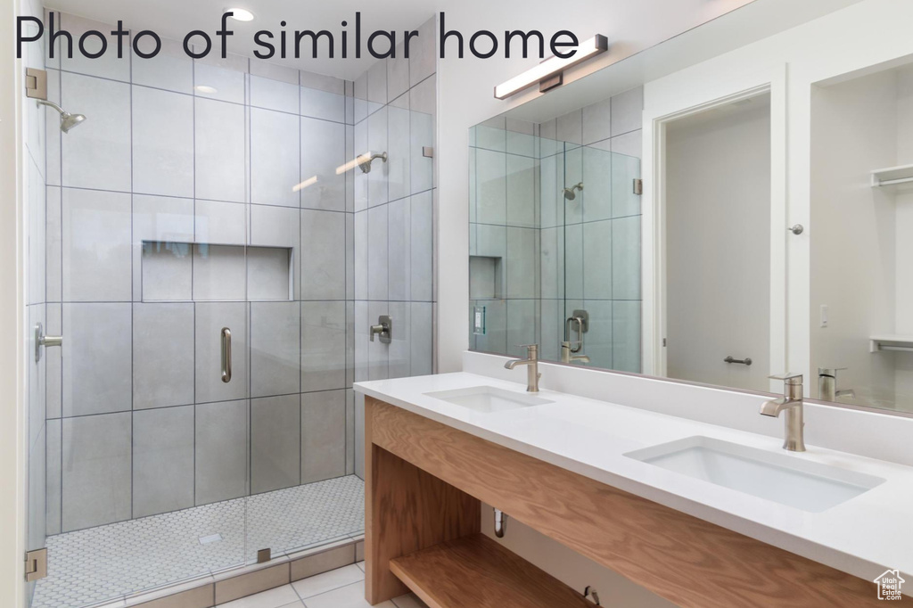 Bathroom featuring a shower with door, double vanity, and tile patterned flooring