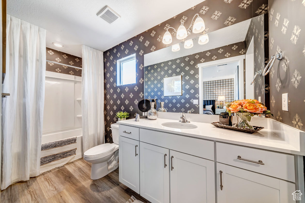 Full bathroom featuring hardwood / wood-style flooring, vanity, toilet, and washtub / shower combination