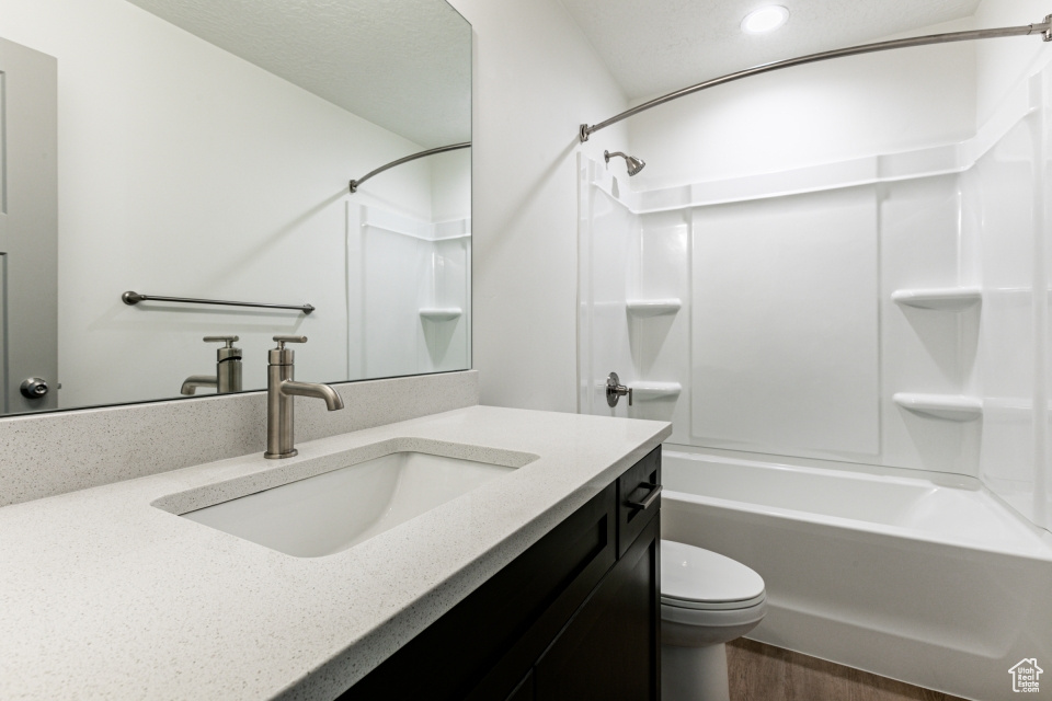 Full bathroom featuring washtub / shower combination, toilet, wood-type flooring, and vanity