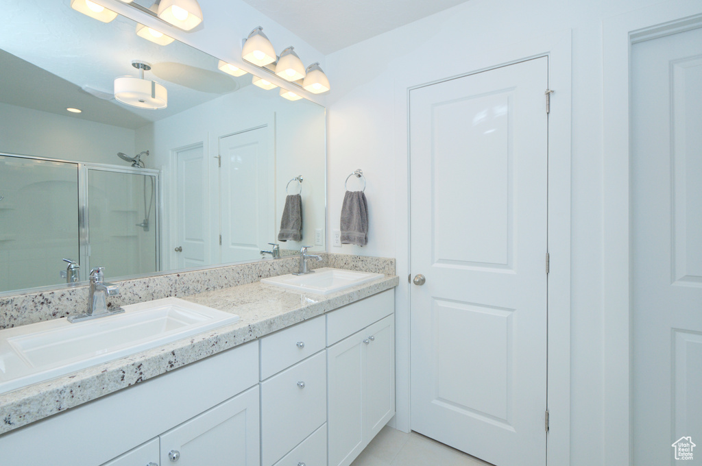 Bathroom featuring a shower with shower door, large vanity, and dual sinks