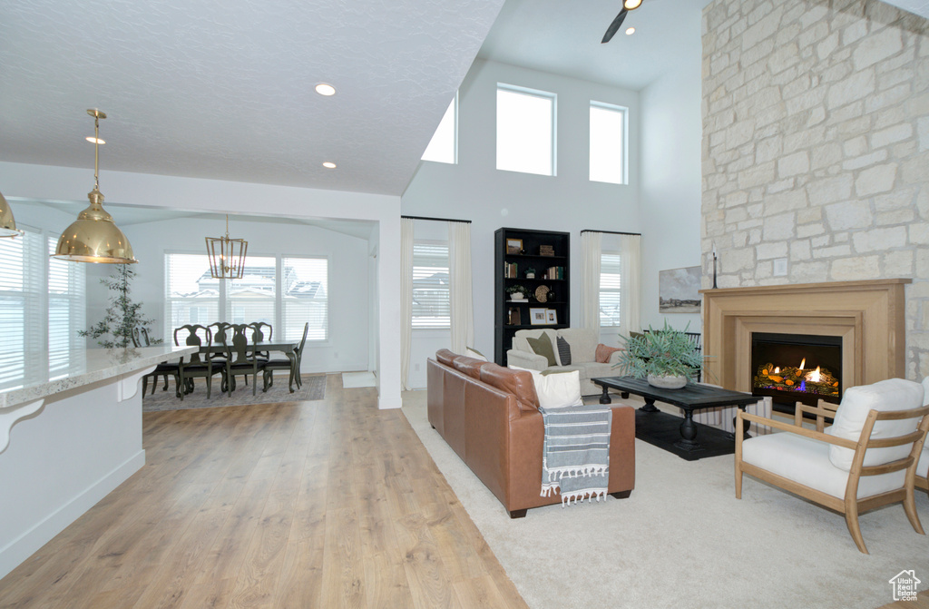 Living room featuring a fireplace, light hardwood / wood-style flooring, a wealth of natural light, and high vaulted ceiling