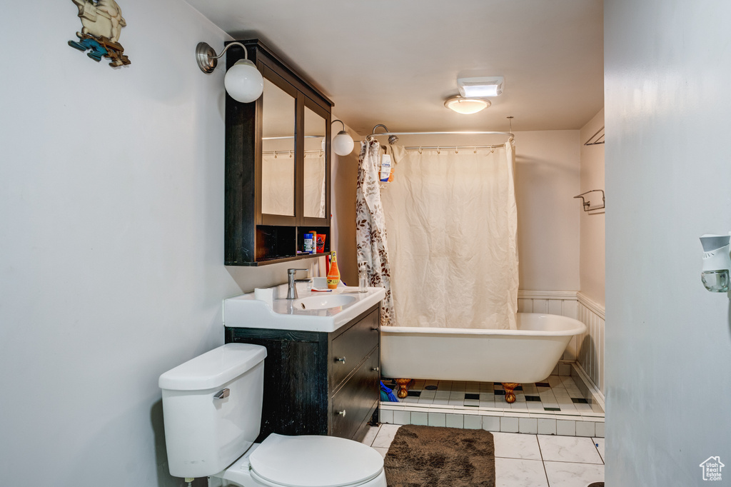 Bathroom with toilet, vanity with extensive cabinet space, and tile floors
