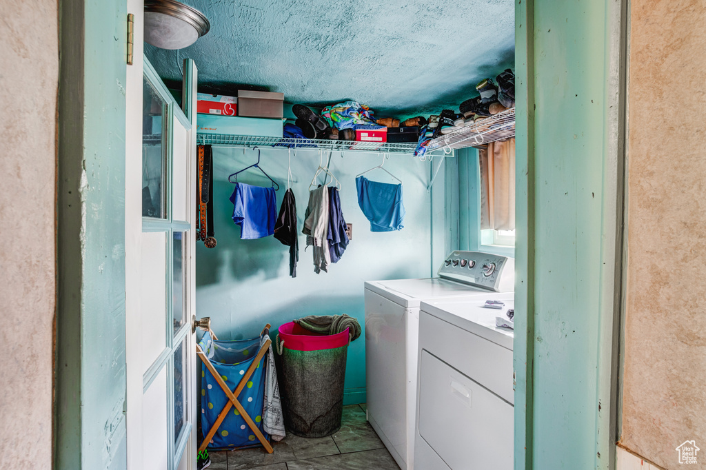 Clothes washing area with light tile floors, washer and clothes dryer, and a textured ceiling