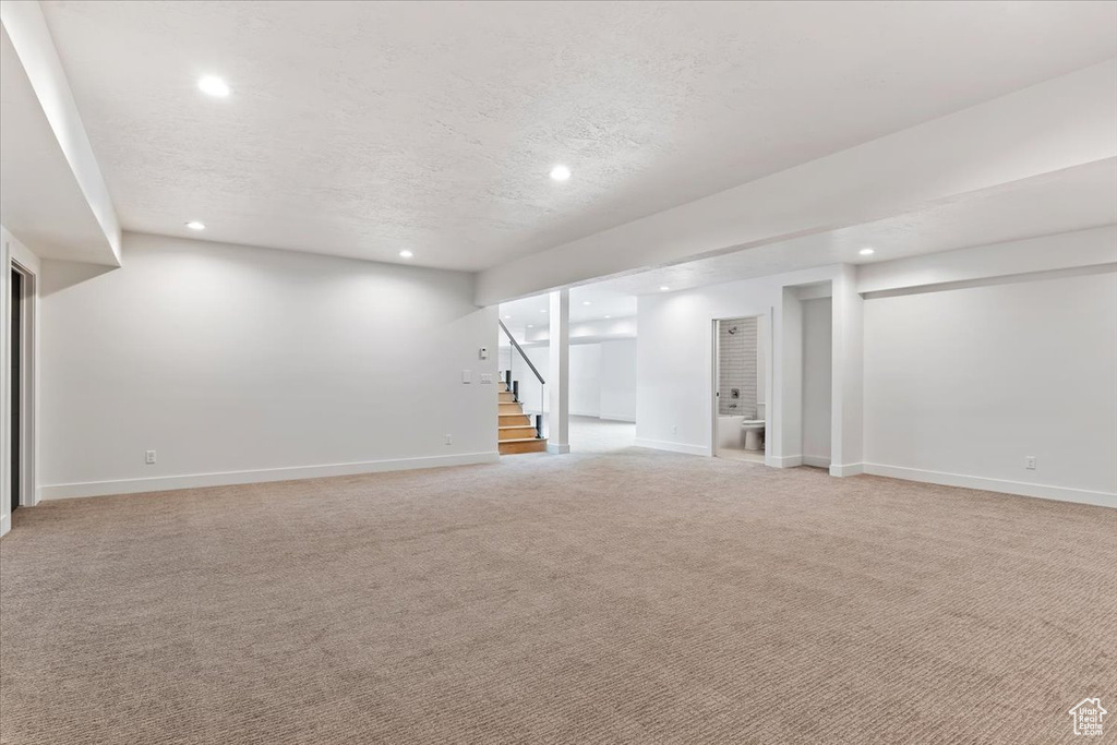 Basement with light colored carpet and a textured ceiling