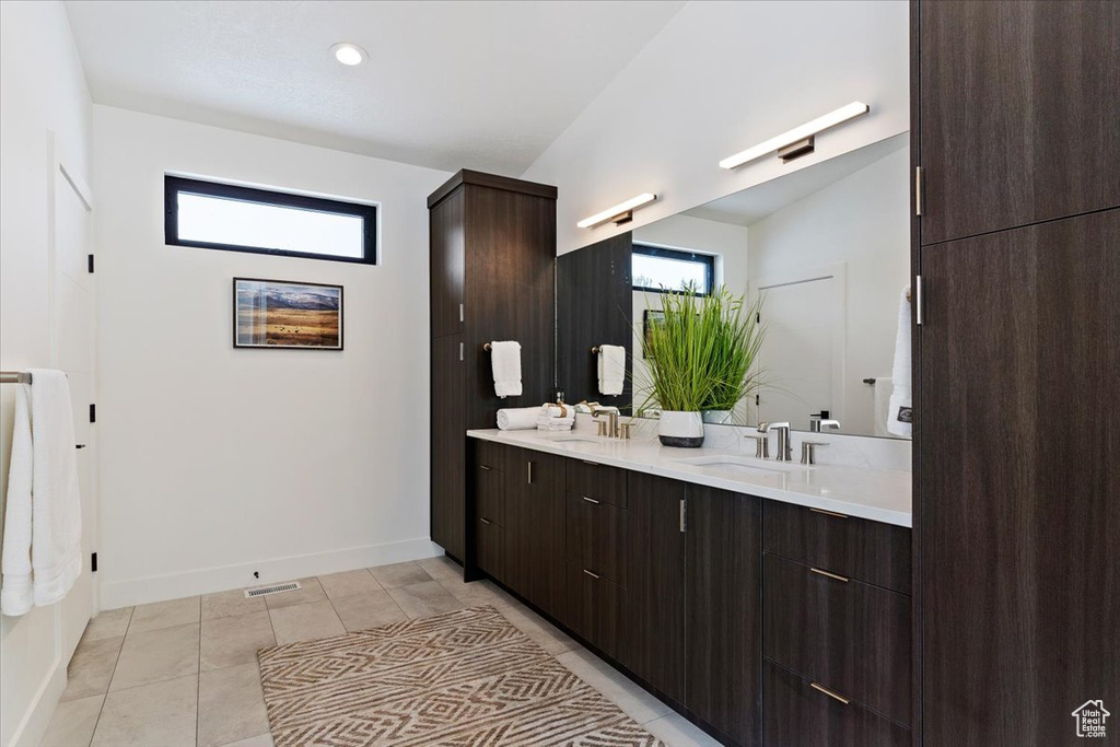 Bathroom featuring vanity with extensive cabinet space, tile floors, and dual sinks