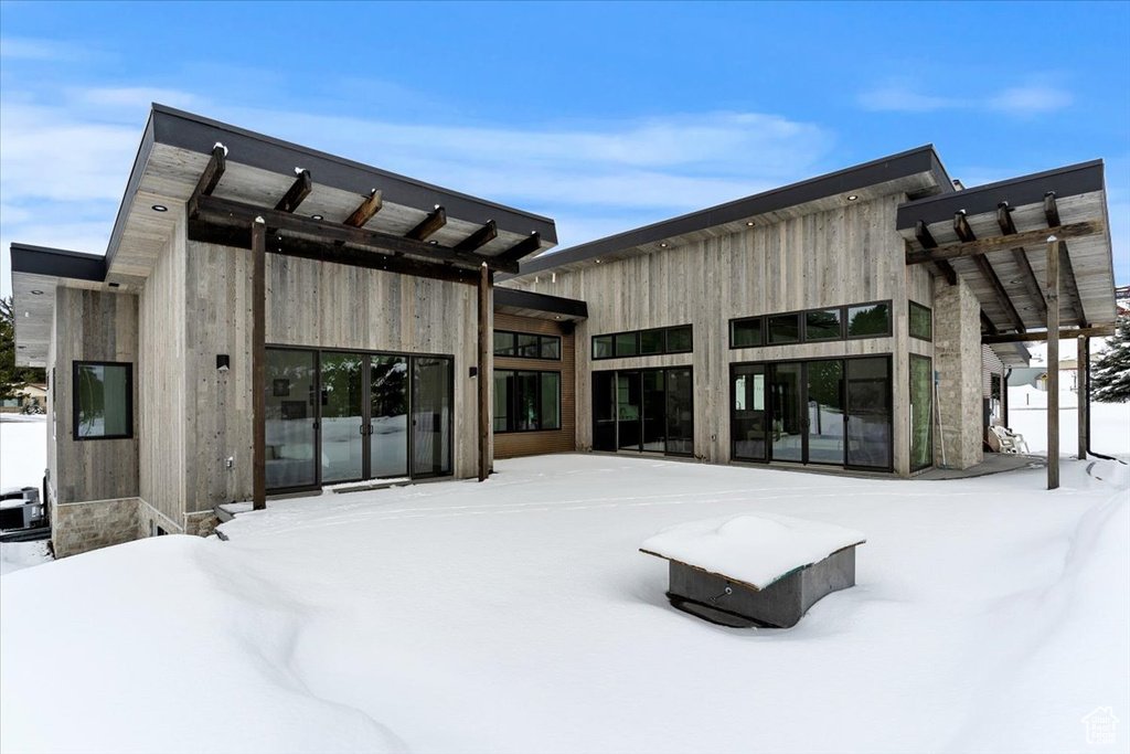 Snow covered house featuring a pergola