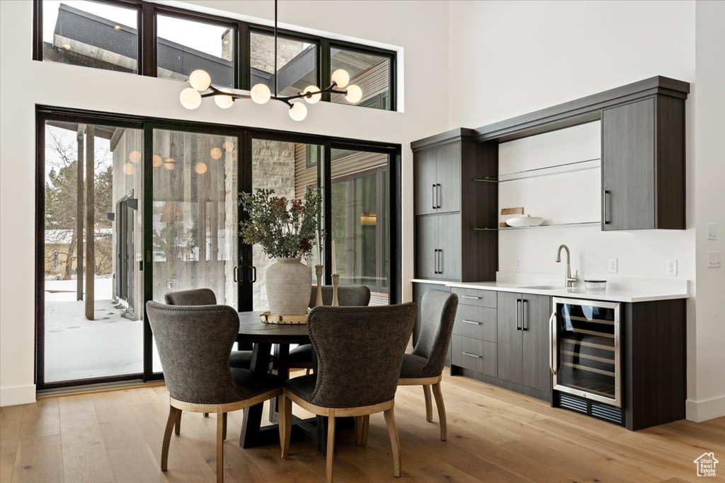 Dining space with wine cooler, a chandelier, light hardwood / wood-style flooring, and sink