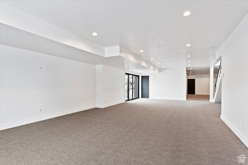 Basement with light colored carpet and a textured ceiling