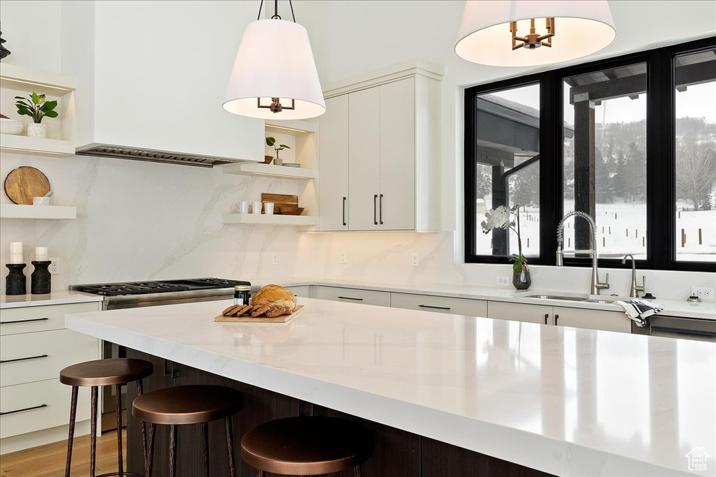 Kitchen with tasteful backsplash, sink, a breakfast bar, white cabinetry, and pendant lighting