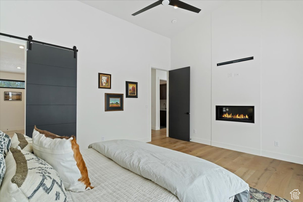 Bedroom featuring ceiling fan, light hardwood / wood-style flooring, and a barn door