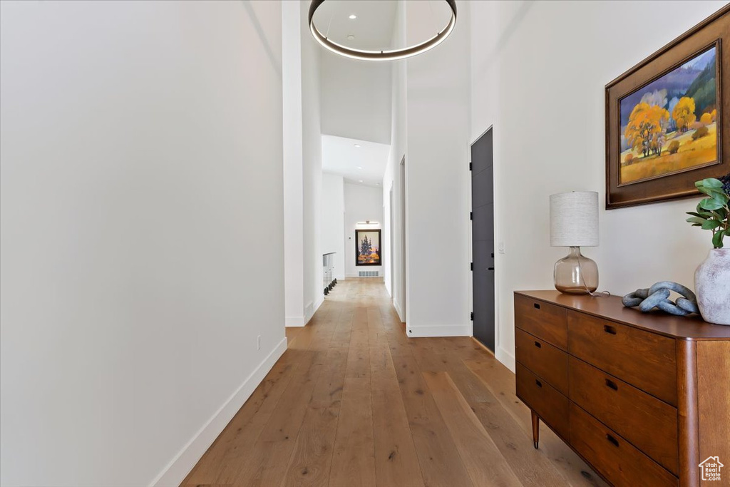 Hallway with a high ceiling and light hardwood / wood-style floors