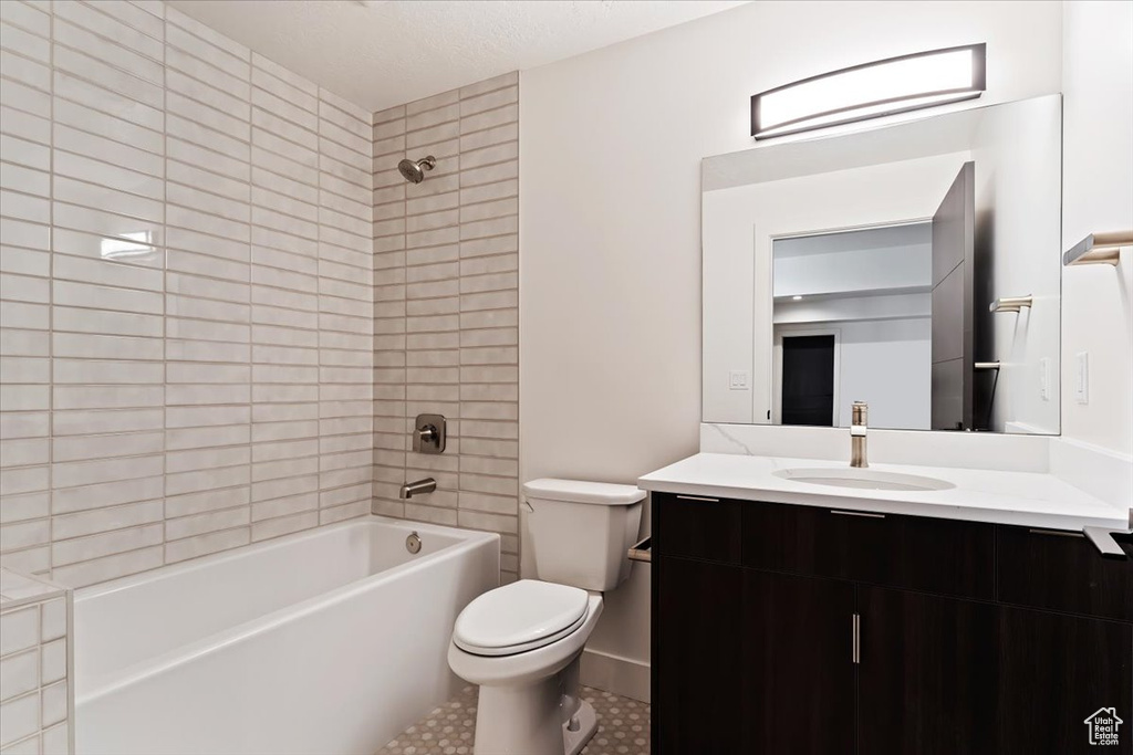 Full bathroom featuring tiled shower / bath combo, tile flooring, large vanity, and toilet