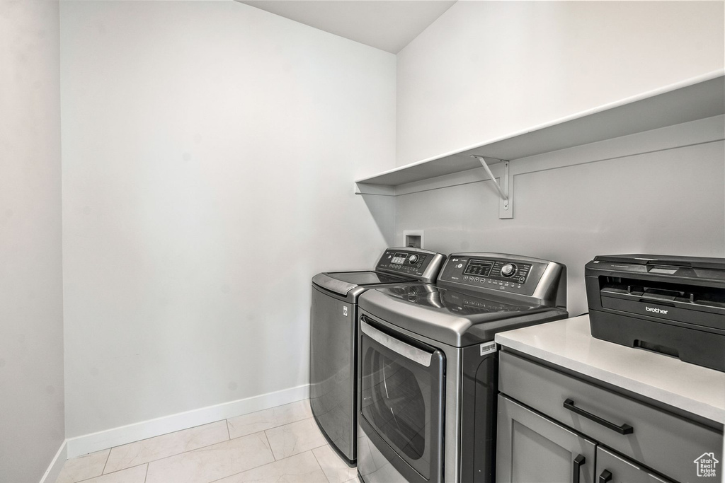 Clothes washing area featuring light tile floors and washer and dryer