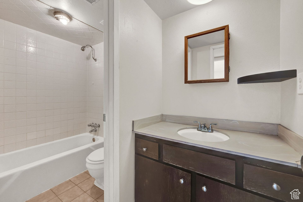 Full bathroom featuring tile flooring, vanity with extensive cabinet space, tiled shower / bath, and toilet