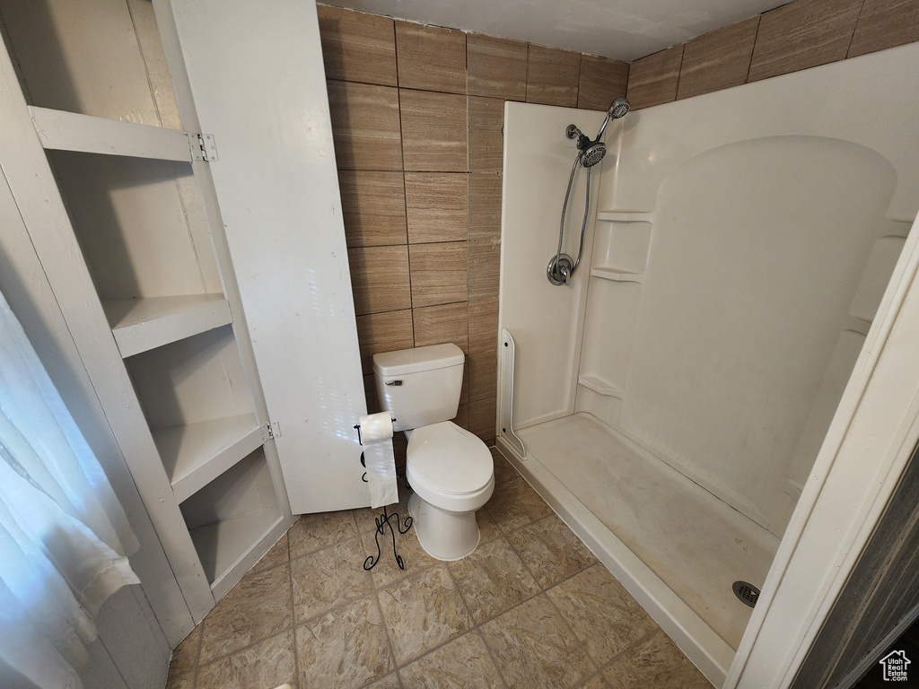 Bathroom with tile flooring, a shower, and toilet
