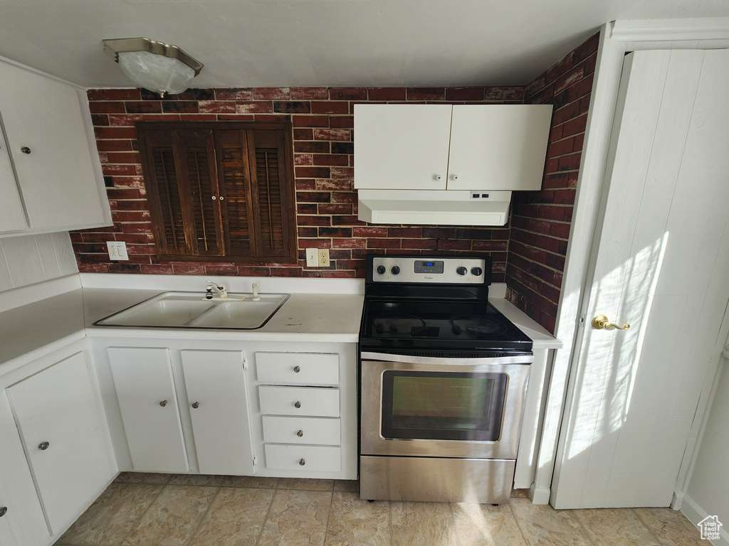 Kitchen with white cabinets, light tile flooring, and electric range