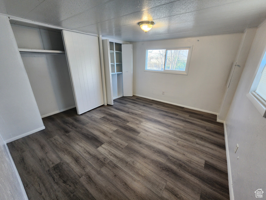 Unfurnished bedroom with a textured ceiling, a closet, and dark wood-type flooring