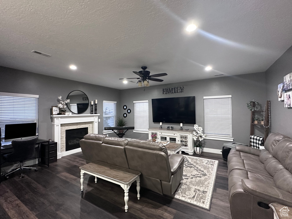 Living room with dark hardwood / wood-style flooring, a textured ceiling, and ceiling fan
